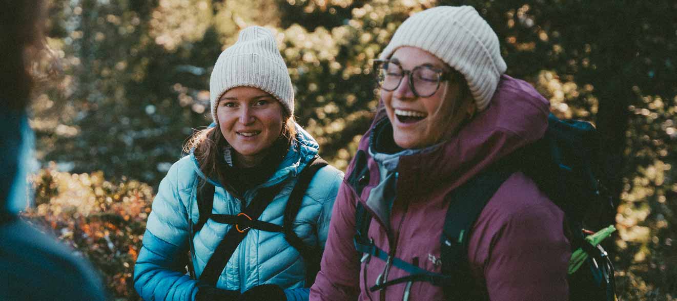 Outdoorjacken für Damen finden Zwei junge Frauen in Outdoorjacke stehen im Wald