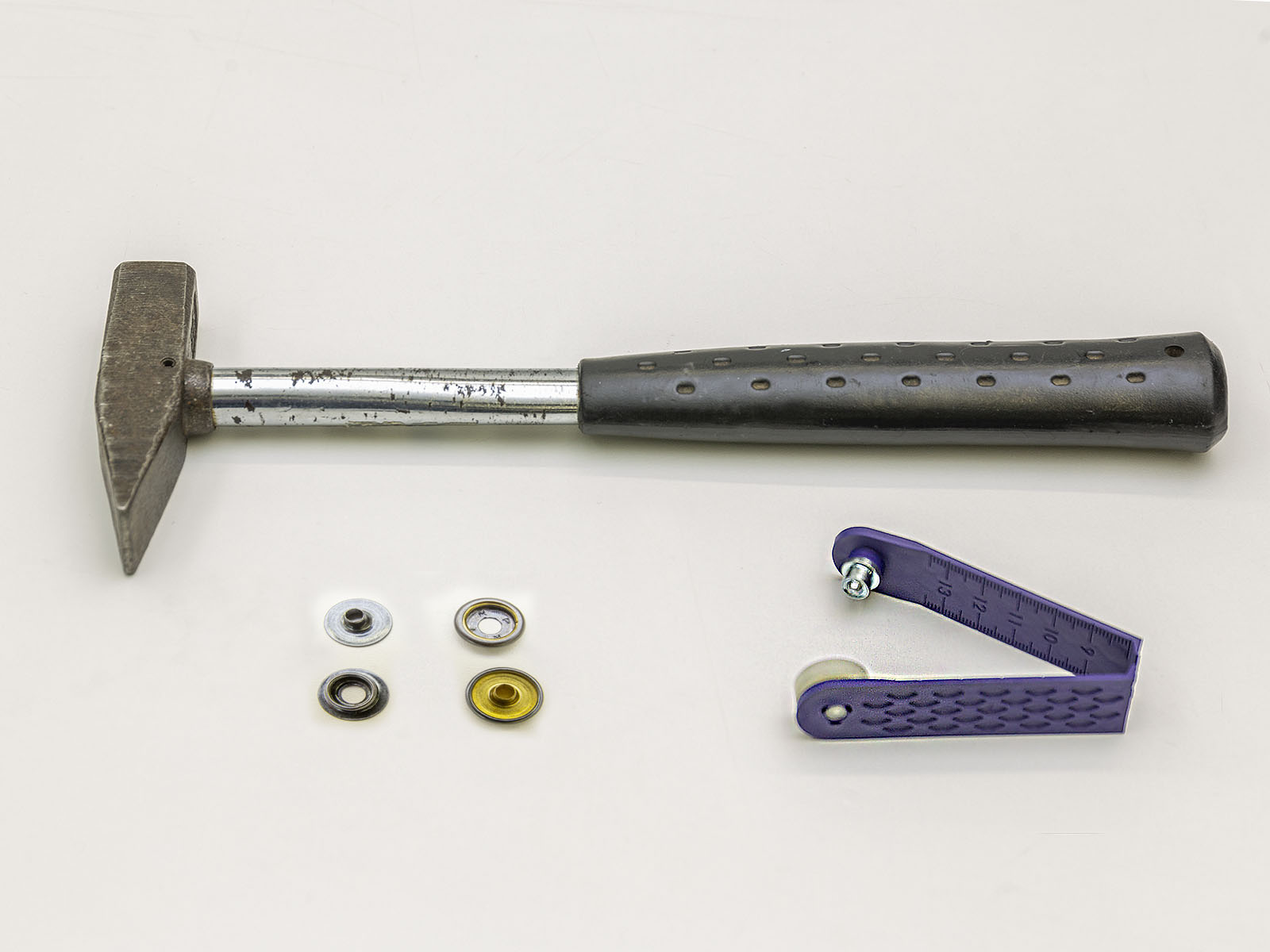 Ein Hammer, ein Ersatz-Druckknopf und ein Lochwerkzeug