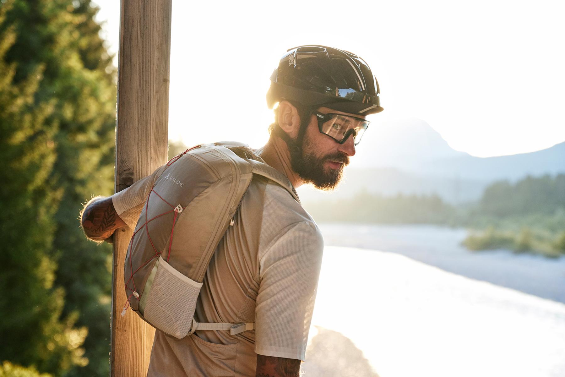 Ein Fahrradfahrer mit Helm und Brille blickt von einer Brücke.