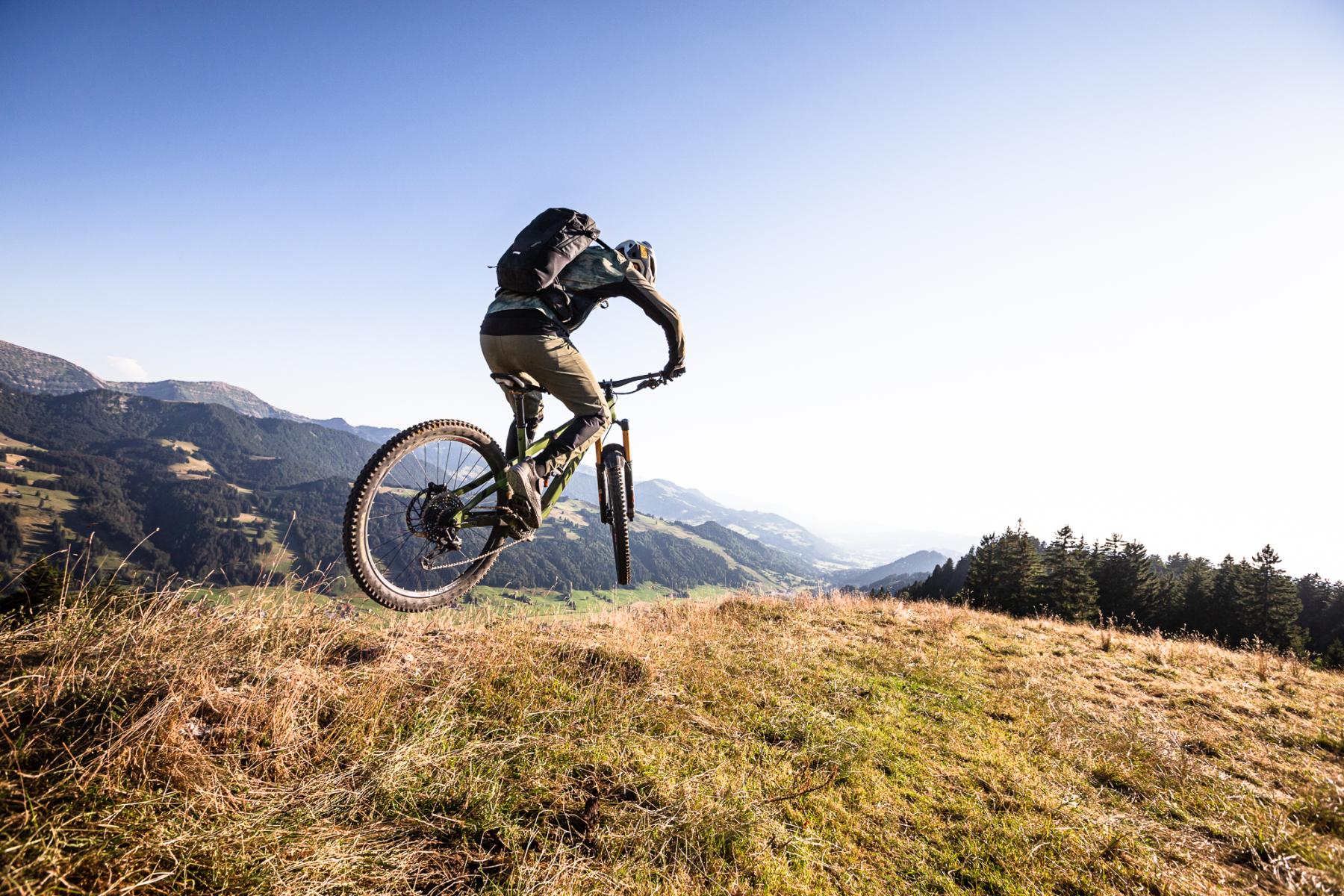 Ein Mann beim Mountainbiken, im Hintergrund sieht man Berge.