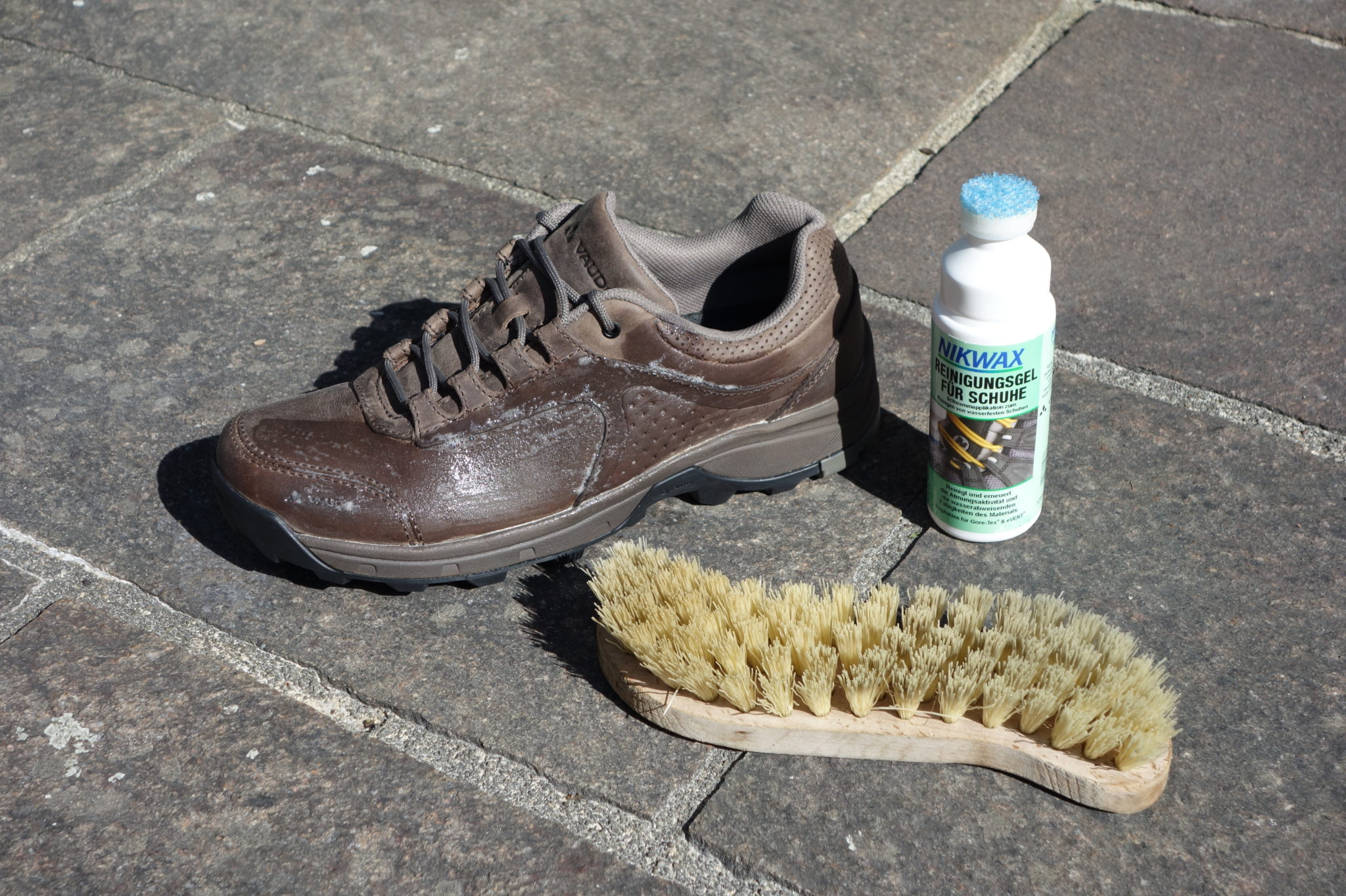 Ein Lederschuh, ein Nikwax-Reinigungsgel und eine Bürste