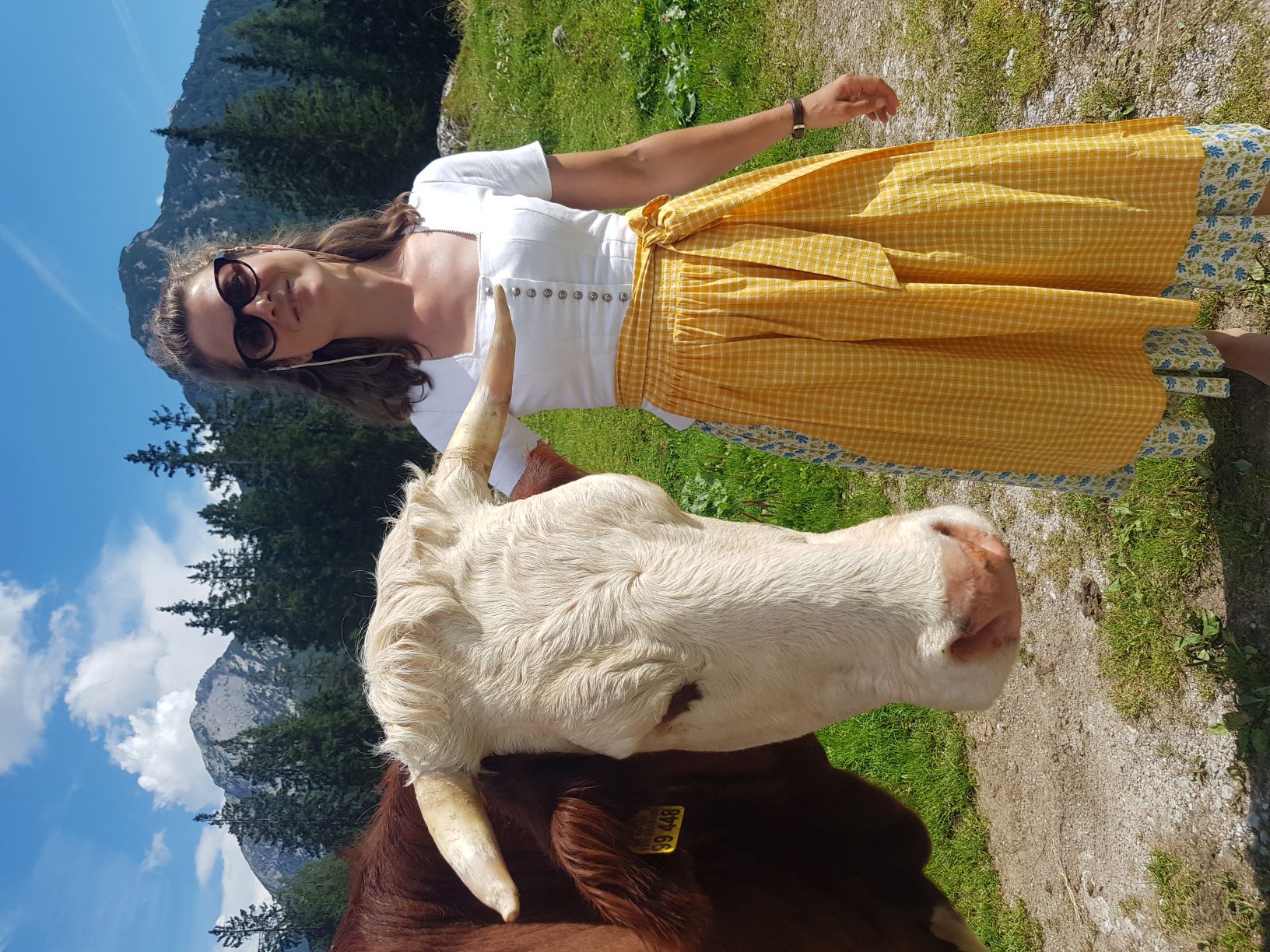 Frau mit Tracht steht neben einer Kuh.