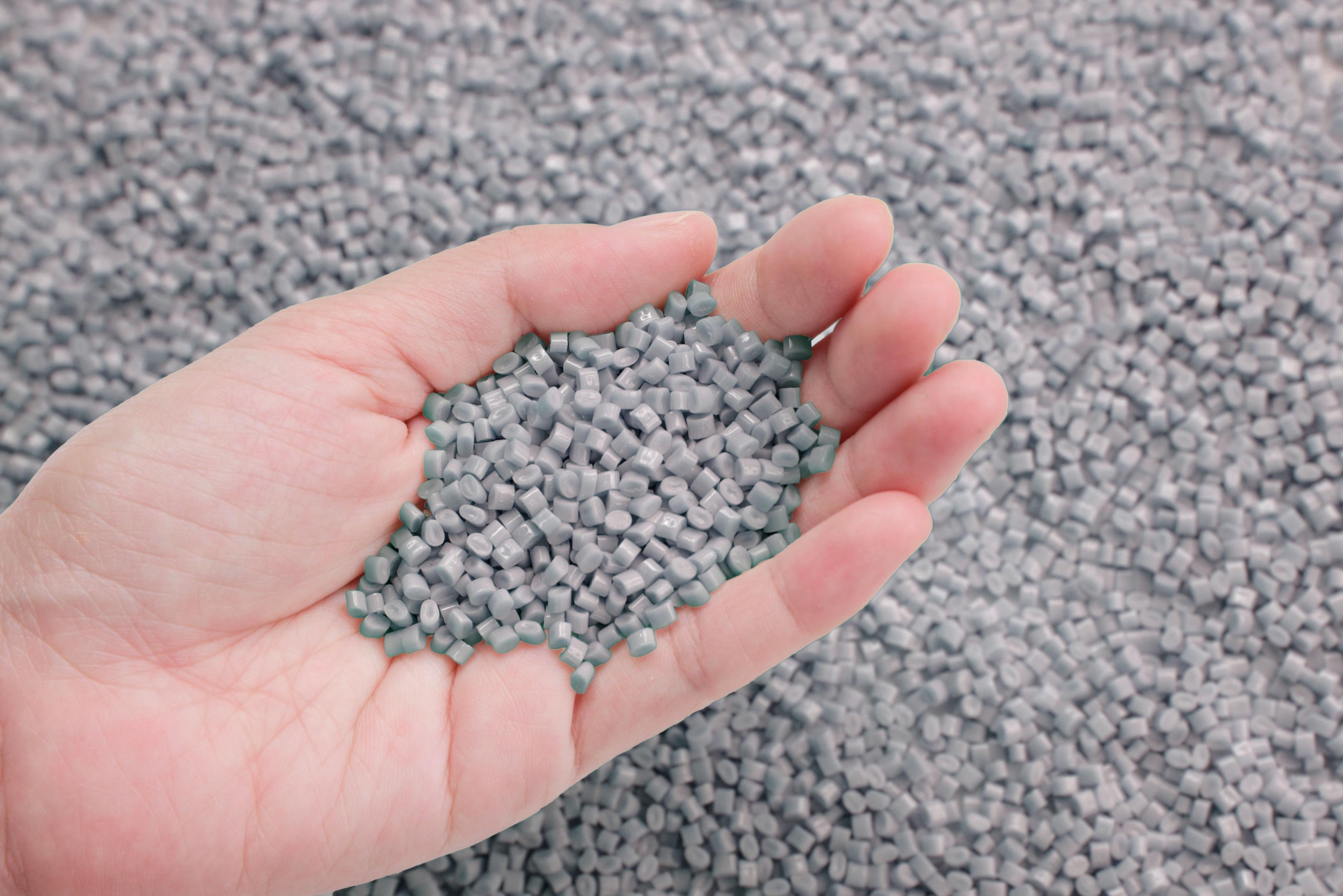 Hand mit Granulat aus recycelten Autoteilen