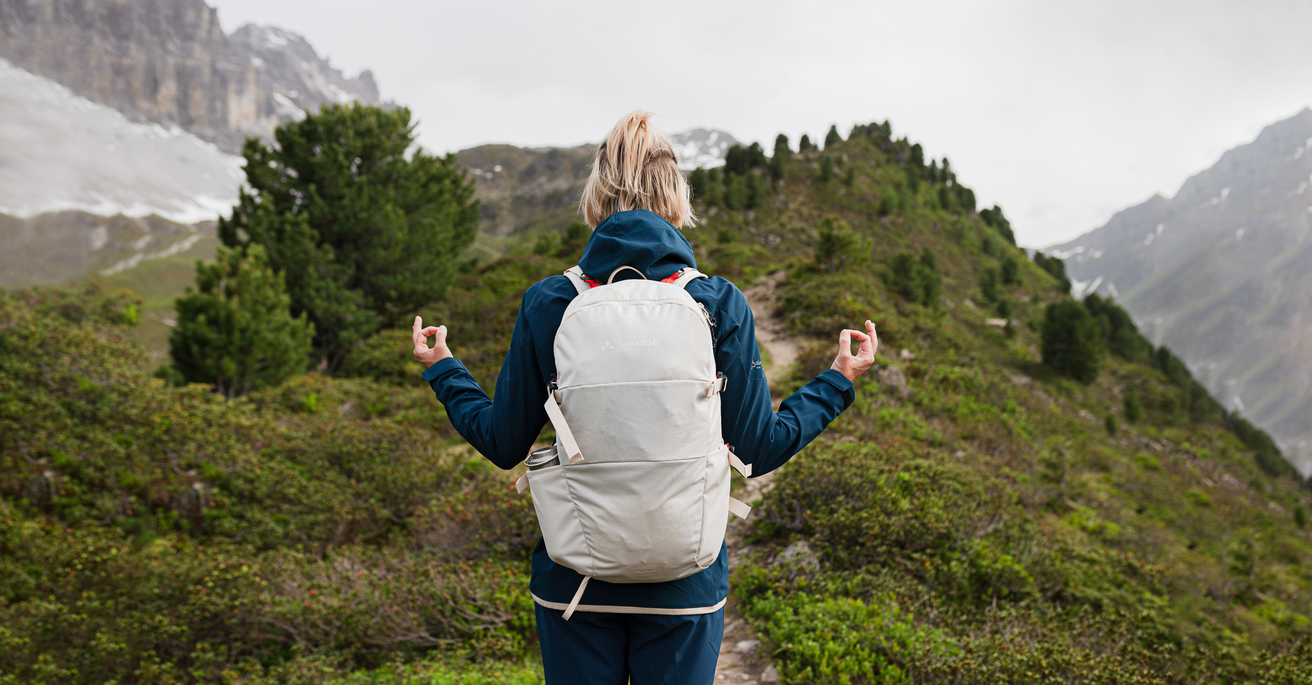 Frau mit kreislauffähigem Rucksack in den Bergen genießt den Moment in der Natur